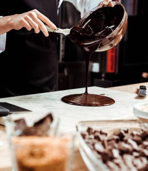 selective focus of chocolatier pouring melted chocolate on marble surface selective focus of chocolatier pouring melted chocolate on marble surface